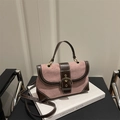 Vintage crossbodytas van roze suède en bruin leer met gouden gesp op een boek - Roze