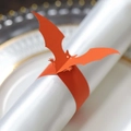 Halloween bat napkin ring made of orange cardstock on a white silk napkin and china plate - Orange Red