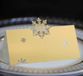 Pale gold laser-cut snowflake place card in pearlescent paper for winter holiday events - Reflective Gold