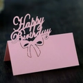 Segnaposto rosa Happy Birthday intagliato al laser con fiocco su sfondo di legno scuro - Rosa