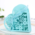 Hollow heart-shaped laser cut wedding candy box in light blue with ribbon bow on ceramic plate - Tiffany Blue