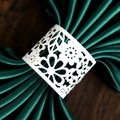 Laser-cut white floral paper napkin rings on dark green satin fabric for party decor - White