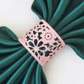 Pink laser-cut floral paper napkin ring with intricate petal design on green satin - Pink