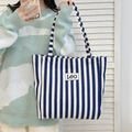 Blue and white striped canvas tote bag with Leo logo displayed on person for casual daily use - Blue