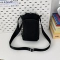 Detail van zwarte nylon crossbody tas met trekkoordsluiting en ritsvak aan de voorkant - Zwart
