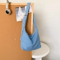 Borsa tote in denim azzurro con ampia tracolla regolabile in un ambiente minimalista - Blu