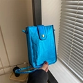 Detail der blauen Handytasche mit Krokodilmuster, glänzendes Leder und goldener Druckknopf - Blau