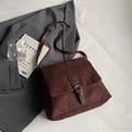 Bolso bandolera de ante marrón oscuro con detalle de hebilla y diseño minimalista - café