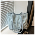 Detail of light blue tote bag showing glossy faux leather texture and bow lacing design - Blue