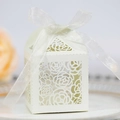 Detailed macro view of laser-cut rose patterns on white cardstock gift box with silk ribbon - Ivory