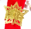 Elegante gouden vlinder servetring met hol ontwerp op een feestelijke rode stof - Reflecterend Goud