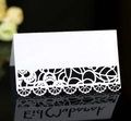 Elegant white laser-cut lace wedding place card on a reflective black surface - White