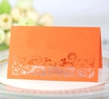 Macro shot of laser-cut orange wedding place card with intricate floral lace patterns - Orange Red