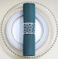 Silver hollow geometric metal napkin ring on green cloth over white gold-rimmed plate - Reflective Silver