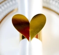 Elegant gold heart napkin ring on a white silk napkin for wedding table decor - Reflective Gold