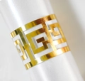 Elegant gold reflective napkin ring with geometric hollow pattern on white fabric - Reflective Gold