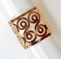 Rose gold hollow-out metal napkin ring with swirl pattern on white satin fabric - Reflective Rose Gold