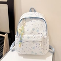Detaillierte Nahaufnahme eines weißen Canvas-Rucksacks mit Sternprint und Vogel-Anhänger - Blau