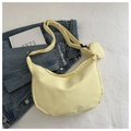 Detail view of a pale yellow nylon hobo bag with a small round detachable pouch charm - Yellow