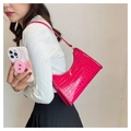 Detail view of pink crocodile embossed faux leather shoulder bag worn by a model - Red