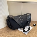 Practical black cylindrical nylon travel bag with wide shoulder strap on beige carpet - 39x19x20 / Black