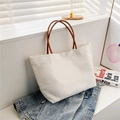 Detalle de bolso cubo de lona blanca con asas marrones sobre chaqueta vaquera - Blanco
