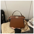 Klassische braune Trapezhandtasche mit goldenem Drehverschluss und Schulterriemen - Kaffeebraun