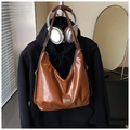 Detail of glossy brown PU leather tote bag with metallic emblem and retro urban style - Brown