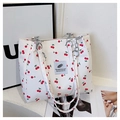 Dettaglio della borsa tote bianca con stampa ciliegia, catena e etichetta in tessuto - Bianco