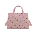Pink crossbody bag with cherry prints and top handle on a clean white background - Pink