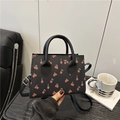 Chic black crossbody bag with red cherry print featuring top handles and long strap - Black