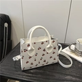 White square tote bag with red cherry pattern featuring top handles and adjustable strap - White