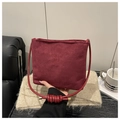 Primer plano detallado del bolso de gamuza granate con texto grabado y correa anudada - Rojo