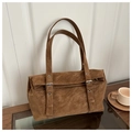 Detail view of a vintage brown faux suede tote bag featuring a buckle flap design on a table - Brown