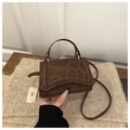 Detailed macro view of the brown textured matte leather and curved flap on mini bag - Brown
