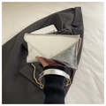 Detail of silver textured envelope bag with golden chain strap held by a person - Silver