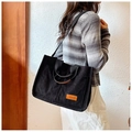 Dettaglio della borsa tote in velluto nero con texture, toppa fashion e manico in pelle - Nero