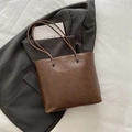 Retro deep brown faux leather tote bag with long straps on a grey office blazer - Brown