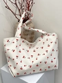 Detail of white canvas tote bag with red cherry prints on a minimalist display stand - Red Cherry Print