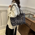 Bolso tote grande de lona negra con patrón de lazos blancos mostrado por una modelo - Negro