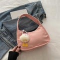 Bolso de hombro chic en nylon rosa con un lindo colgante de peluche sobre fondo denim - Rosa