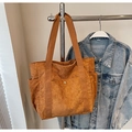 Close-up of brown corduroy tote bag featuring a front pocket with a metal snap button - Tan