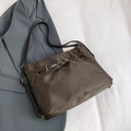 Borsa tote marrone scuro con fibbia in metallo dorato su sfondo blazer grigio elegante - Marrone