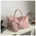 Detalle del bolso de viaje rosa grande y monedero a juego sobre un mueble de casa - Rosa