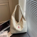 Close-up of a blue and yellow checkered canvas tote with a handmade tomato patch label - Beige