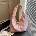 Close-up of pink and blue plaid canvas bag with handmade woven label and cream bow detail - Pink