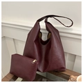 Dettaglio della borsa hobo in pelle bordeaux e pochette coordinata su un tavolo in legno - Rosso