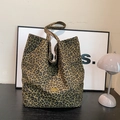 Close-up of leopard print tote bag fabric with handmade golden metal logo tag detail - Leopard Double-Sided