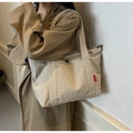 Detailweergave van de grote beige nylon shopper met fashion-label gedragen op een jas - Wit