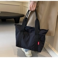 Detail van de zwarte nylon shopper met brede banden en een rood modieus label erop - Zwart